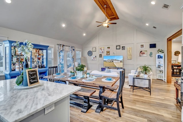 dining space featuring light wood-style floors, ceiling fan, visible vents, and a decorative wall