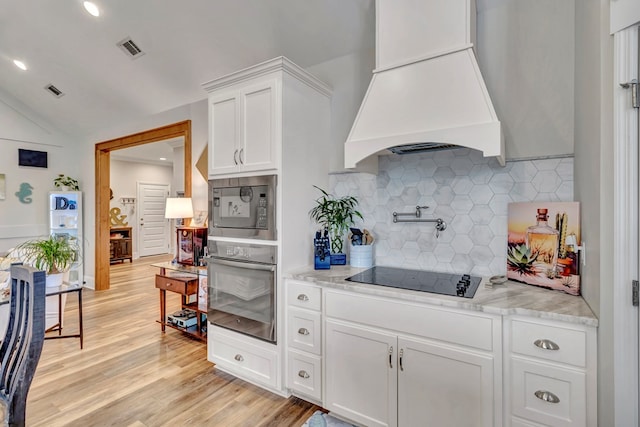 kitchen with visible vents, white cabinets, custom range hood, oven, and black electric stovetop