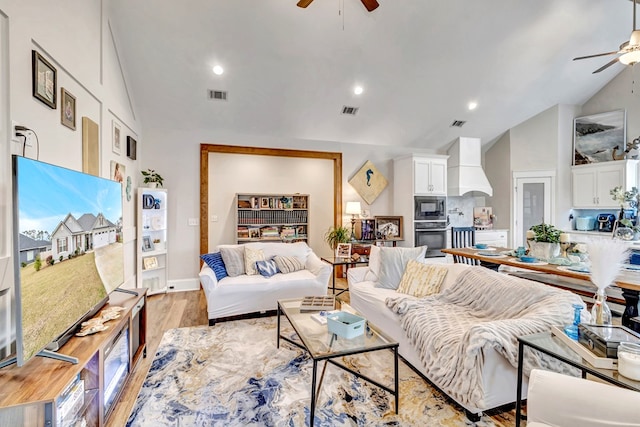 living room with visible vents, high vaulted ceiling, a ceiling fan, and light wood-style floors