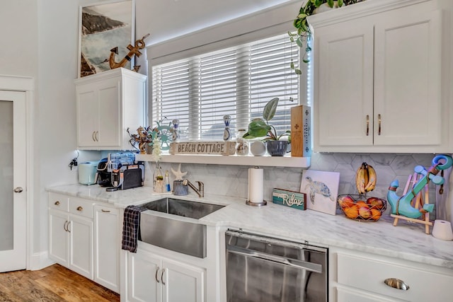 kitchen with tasteful backsplash, a sink, light stone counters, and white cabinets