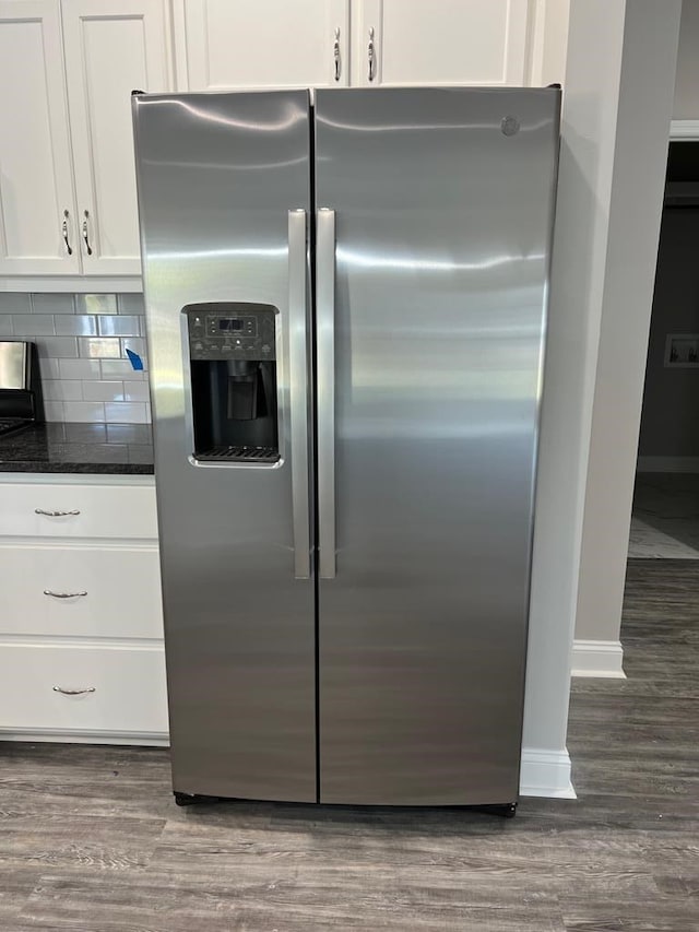 kitchen with white cabinets, stainless steel fridge, decorative backsplash, and dark wood-type flooring