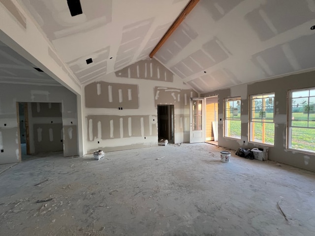 unfurnished living room with beamed ceiling and high vaulted ceiling