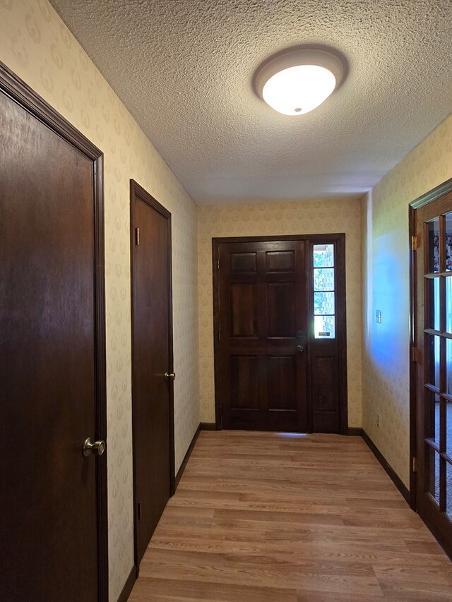 617 Ledgedale Cir, Valdosta, GA 31602 - doorway to outside with wallpapered walls, light wood-style flooring, and a textured ceiling