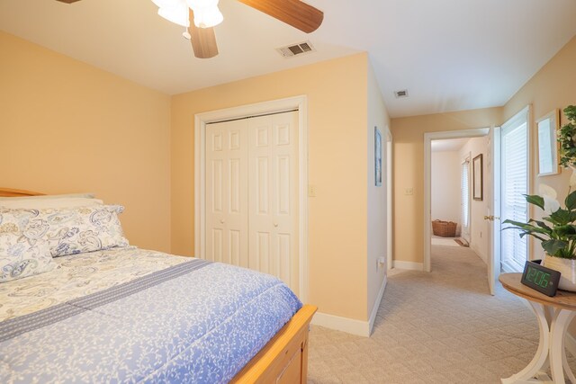 bedroom featuring ceiling fan, light colored carpet, and a closet