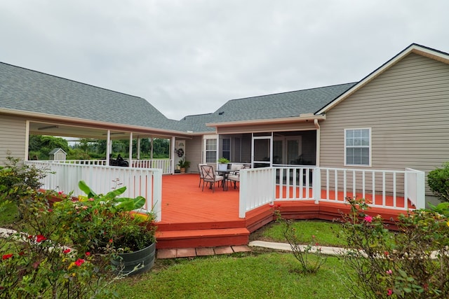 wooden deck with a lawn and a sunroom