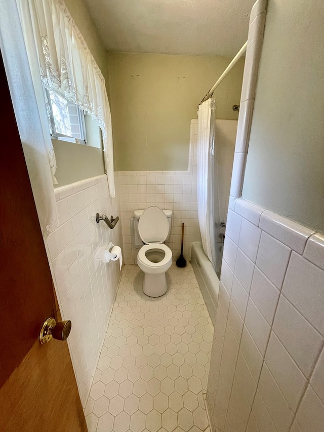 bathroom featuring tile patterned floors, toilet, tile walls, and shower / tub combo with curtain