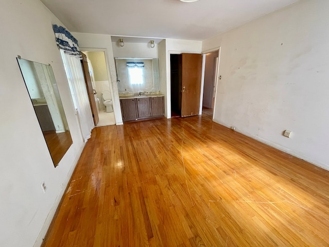 unfurnished bedroom featuring light hardwood / wood-style floors, sink, and connected bathroom