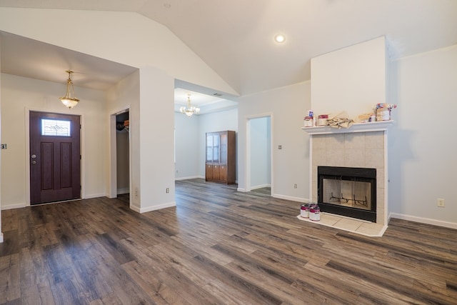 entrance foyer with a tiled fireplace, dark wood-type flooring, high vaulted ceiling, and a chandelier