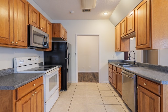 kitchen featuring appliances with stainless steel finishes, sink, a textured ceiling, and light tile patterned floors