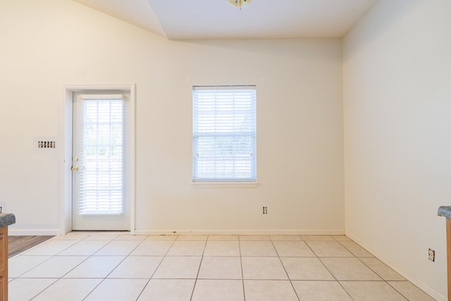 tiled spare room with vaulted ceiling and a wealth of natural light