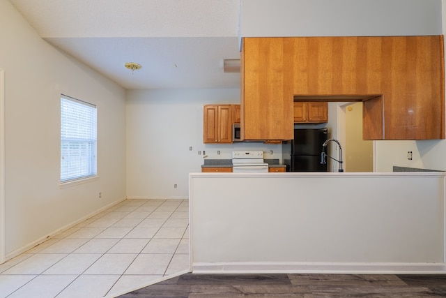 kitchen featuring white electric stove, black fridge, sink, and light tile patterned floors