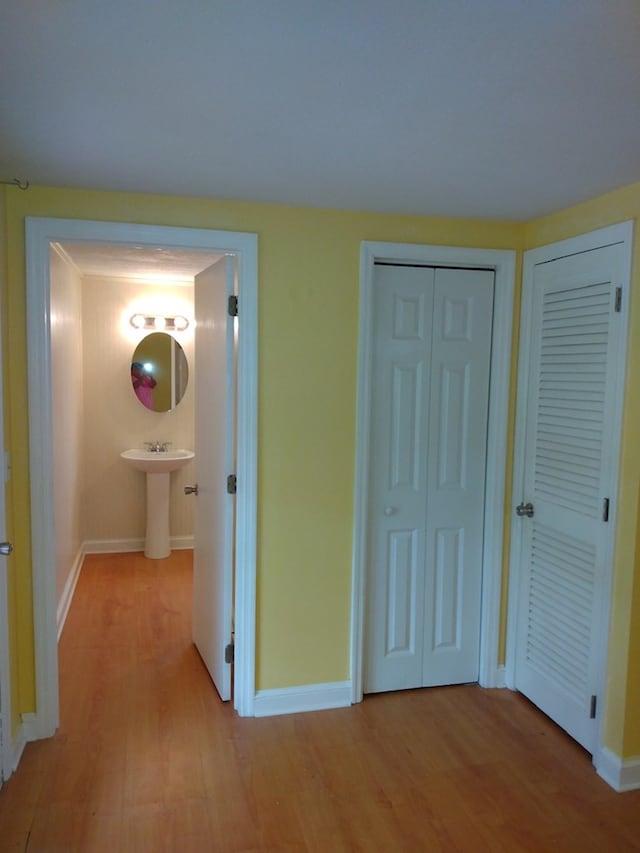 unfurnished bedroom featuring light hardwood / wood-style floors, ensuite bath, multiple closets, and sink