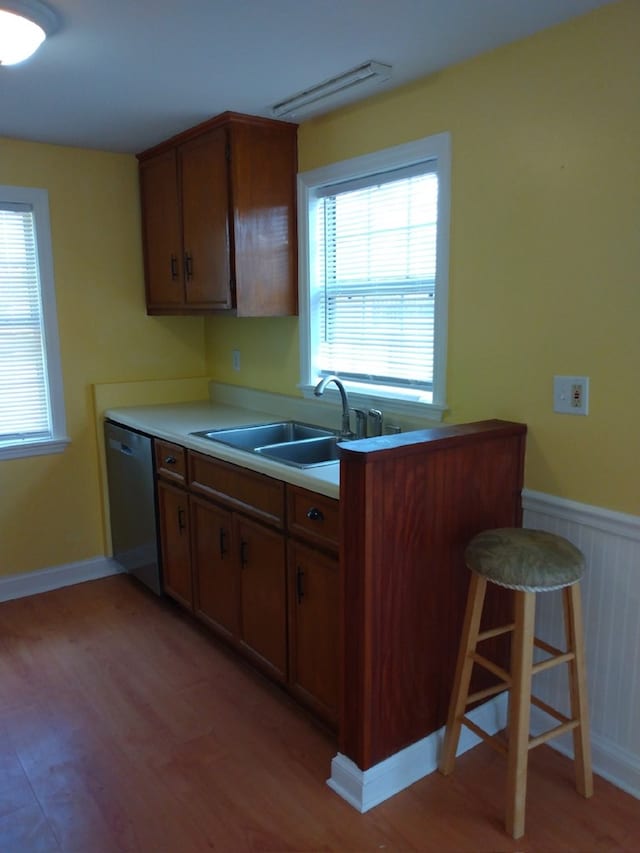 kitchen featuring light hardwood / wood-style floors, stainless steel dishwasher, a breakfast bar area, and sink