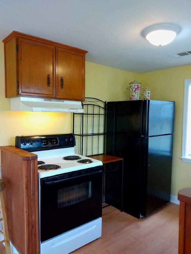 kitchen featuring electric range, black fridge, and light hardwood / wood-style flooring