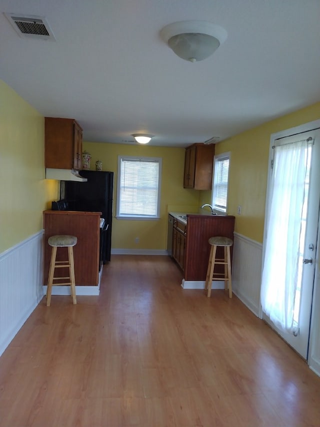 kitchen with a kitchen breakfast bar, kitchen peninsula, sink, and light wood-type flooring