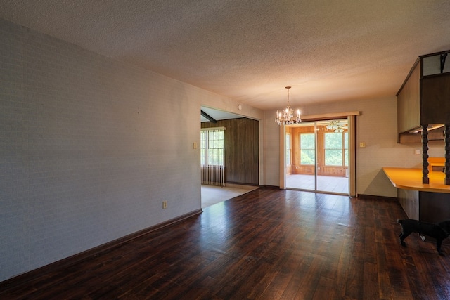 unfurnished dining area with a chandelier, a textured ceiling, and wood finished floors
