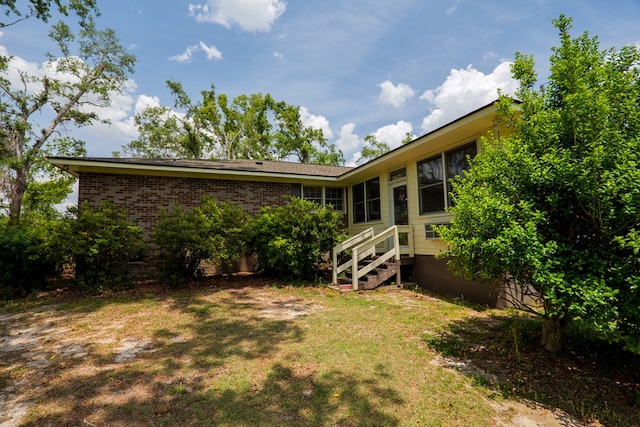 back of property featuring brick siding and a lawn
