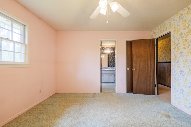 unfurnished bedroom featuring baseboards, ensuite bathroom, and carpet