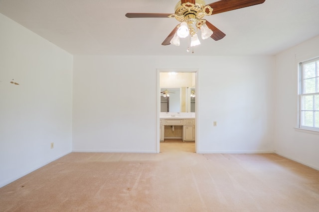 unfurnished bedroom featuring light carpet, connected bathroom, and baseboards