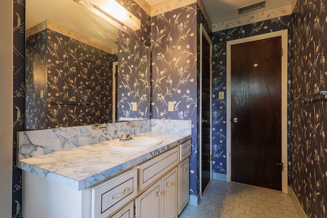 bathroom featuring tile patterned flooring, visible vents, vanity, and wallpapered walls