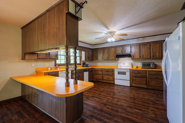 kitchen with a peninsula, white appliances, dark wood-type flooring, under cabinet range hood, and light countertops