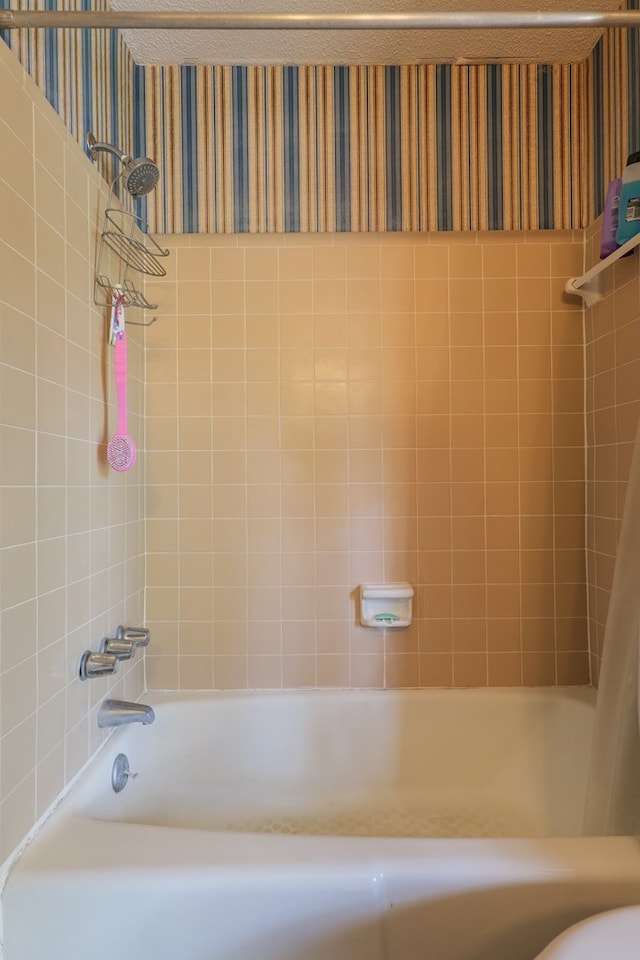 bathroom with shower / bath combo with shower curtain and wallpapered walls