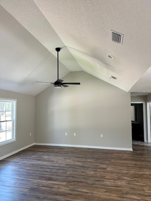 spare room with dark hardwood / wood-style floors, ceiling fan, lofted ceiling, and a textured ceiling