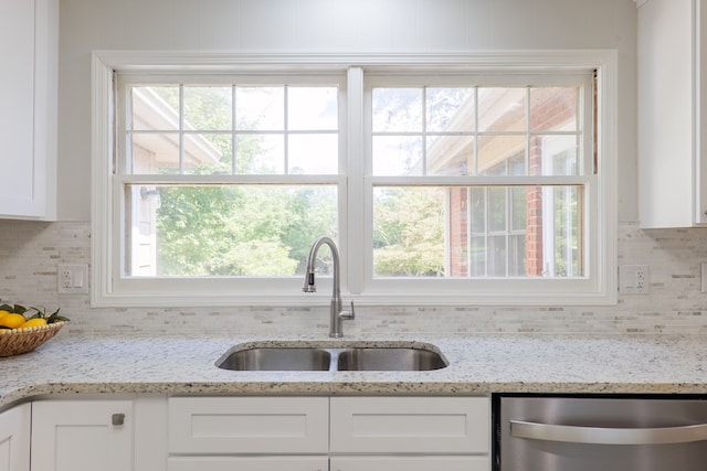 kitchen featuring a sink, white cabinets, stainless steel dishwasher, and backsplash