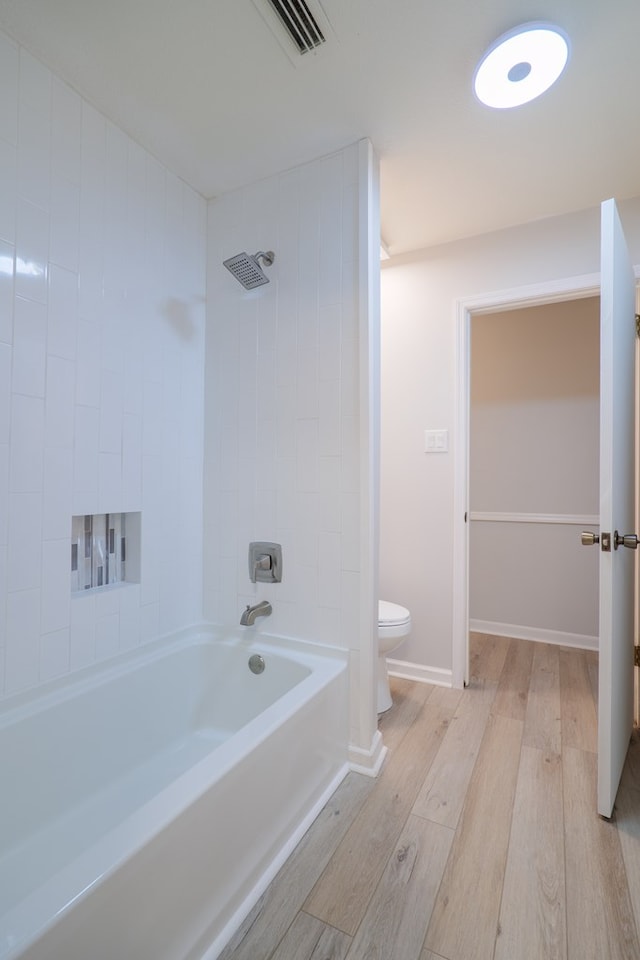 full bath featuring visible vents, wood finished floors, toilet, baseboards, and shower / tub combination