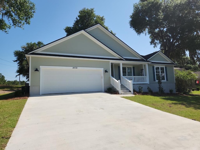 ranch-style home featuring covered porch, a front yard, and a garage