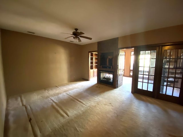 unfurnished living room featuring ceiling fan, light carpet, and french doors