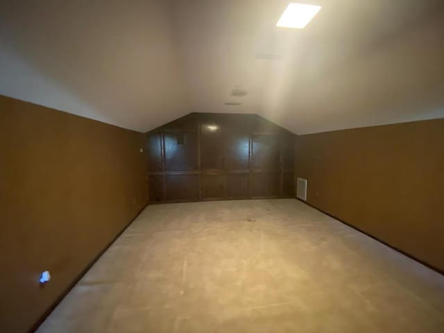 bonus room with light carpet and vaulted ceiling