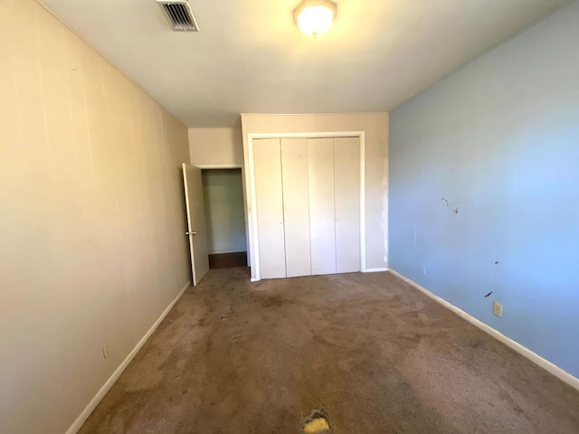 unfurnished bedroom with dark carpet and a closet