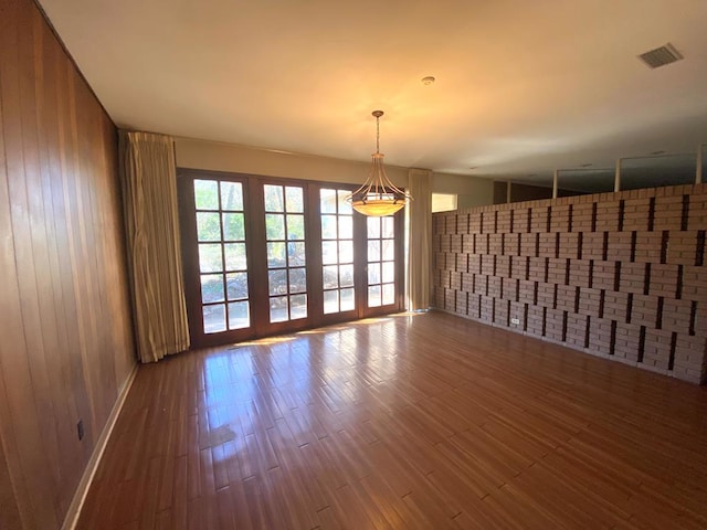 unfurnished room with wood walls, wood-type flooring, and french doors