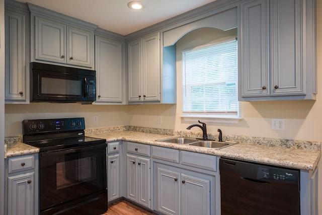 kitchen featuring sink, black appliances, and light hardwood / wood-style flooring