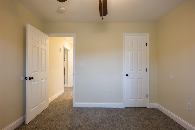 unfurnished bedroom with dark carpet and ceiling fan