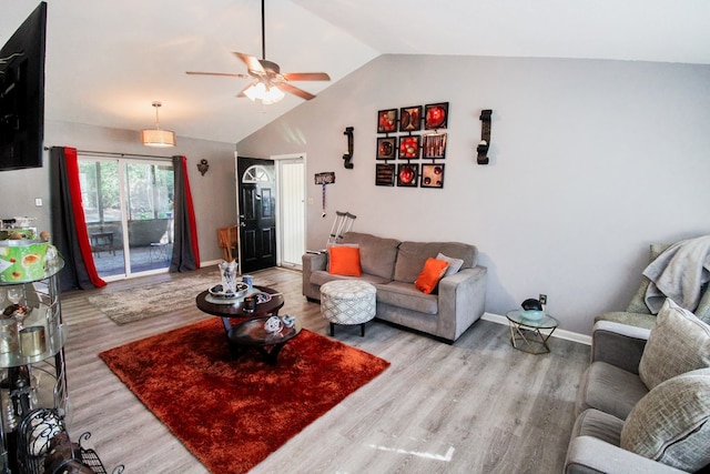 living room with ceiling fan, light hardwood / wood-style floors, and vaulted ceiling