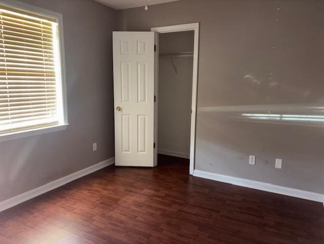 unfurnished bedroom with a closet, baseboards, and wood finished floors