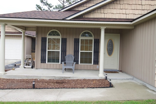 doorway to property featuring an attached garage, a porch, and a shingled roof