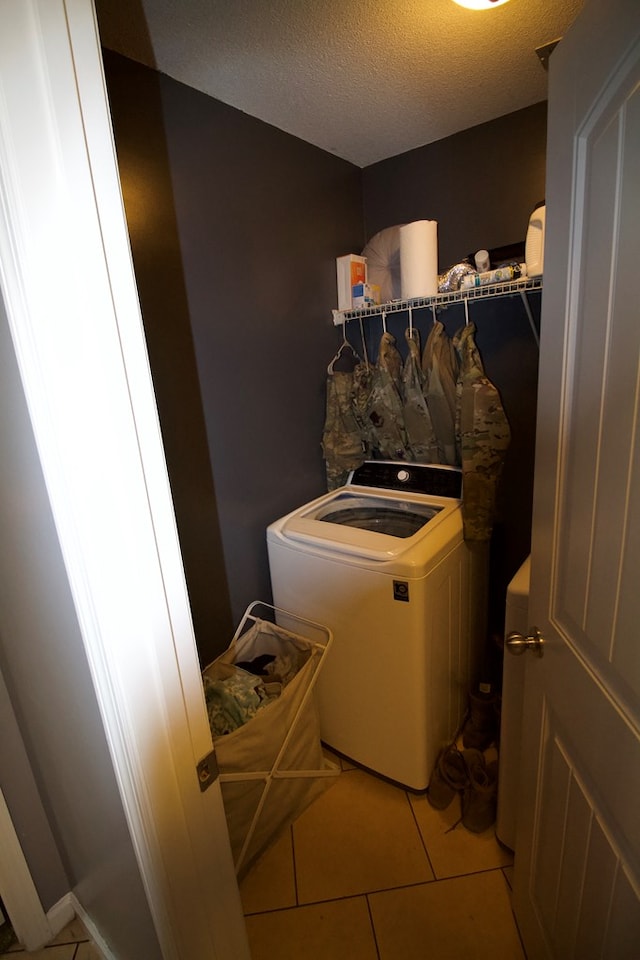 laundry area with laundry area, washer and clothes dryer, a textured ceiling, and light tile patterned flooring