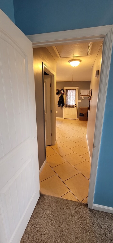 hall featuring attic access, baseboards, and light tile patterned floors