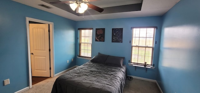 carpeted bedroom with a raised ceiling, visible vents, baseboards, and multiple windows