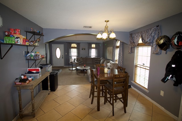 dining area featuring arched walkways, plenty of natural light, visible vents, and a notable chandelier