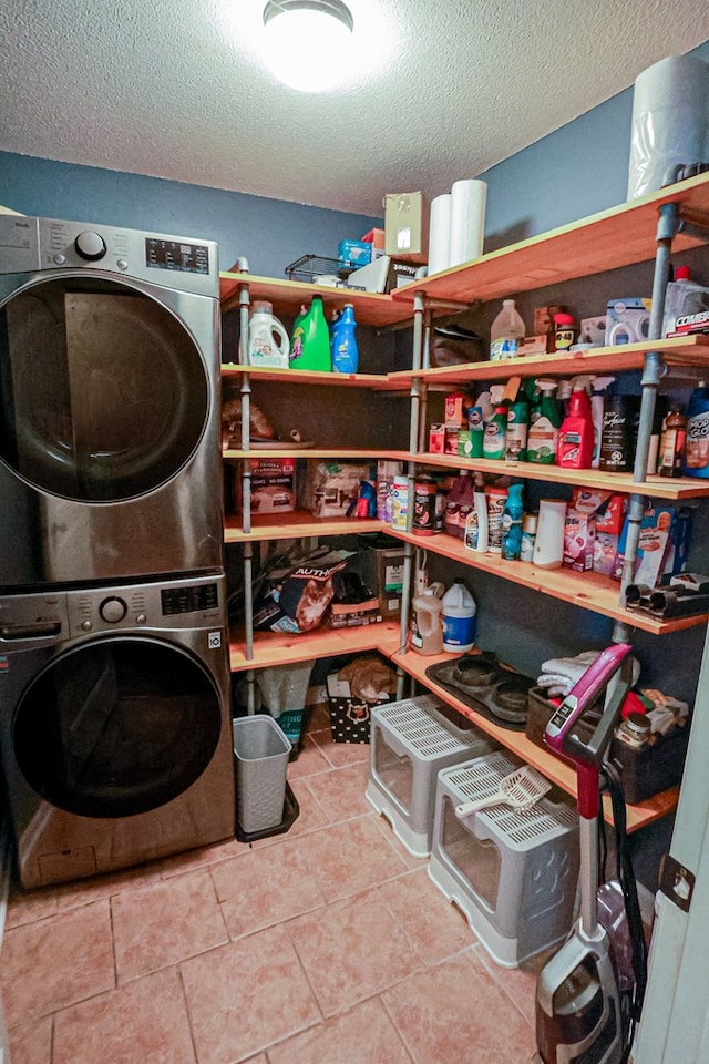 laundry room with laundry area, a textured ceiling, stacked washing maching and dryer, and tile patterned flooring
