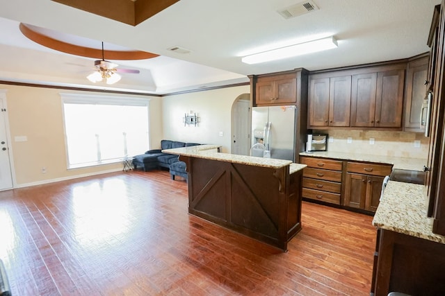 kitchen with arched walkways, a tray ceiling, visible vents, and stainless steel refrigerator with ice dispenser