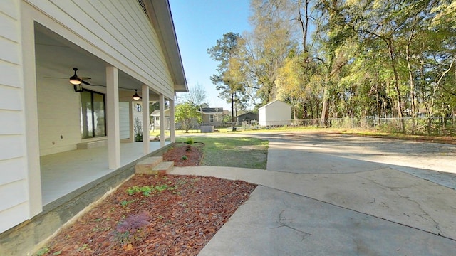 view of yard with fence, covered porch, and ceiling fan