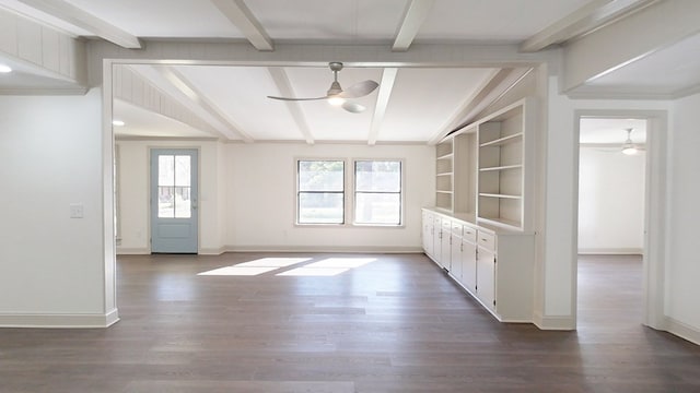 interior space featuring built in shelves, dark wood-type flooring, a ceiling fan, lofted ceiling with beams, and baseboards