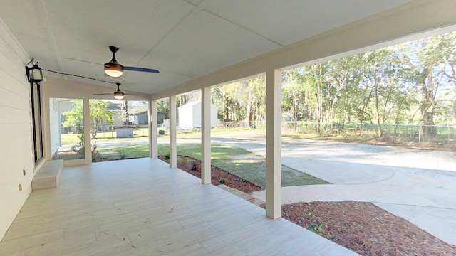 view of patio / terrace with an outbuilding, ceiling fan, and fence