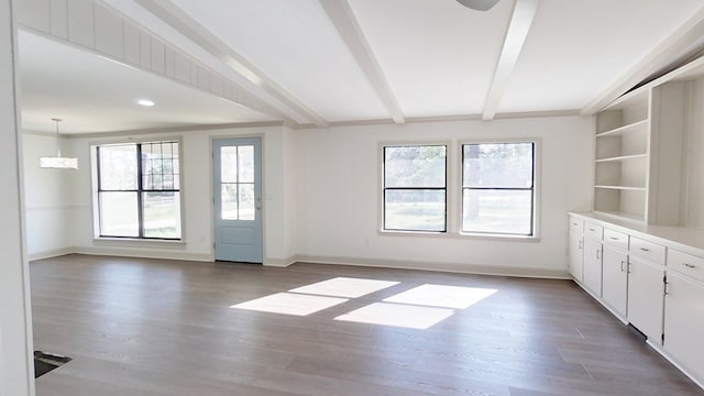 empty room featuring baseboards, beam ceiling, and wood finished floors