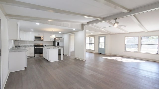 kitchen featuring a sink, dark wood finished floors, open floor plan, stainless steel appliances, and vaulted ceiling with beams